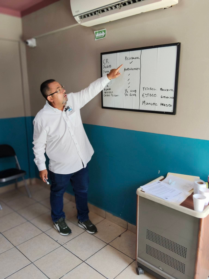 Santiago explicando un plan de trabajo en pizarrón